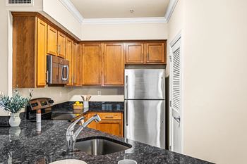 A kitchen with a granite countertop and wooden cabinets.